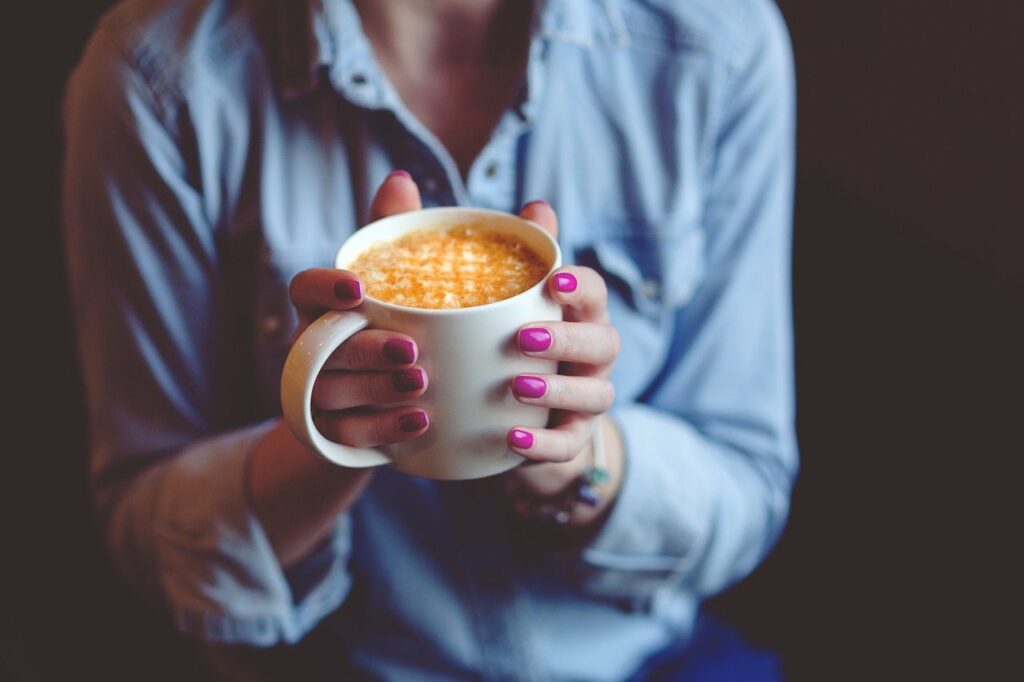 Frau hält Kaffee in den Händen lange Nägel Gesundes Wachstum Ihrer Nägel Tipps und Tricks