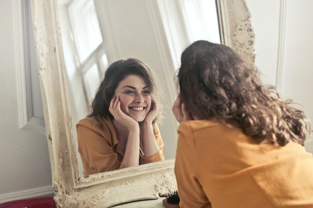 Frau betrachtet ihr Gesicht im Spiegel lächeln Microneedling Falten schlimmer als vorher Nachher besser